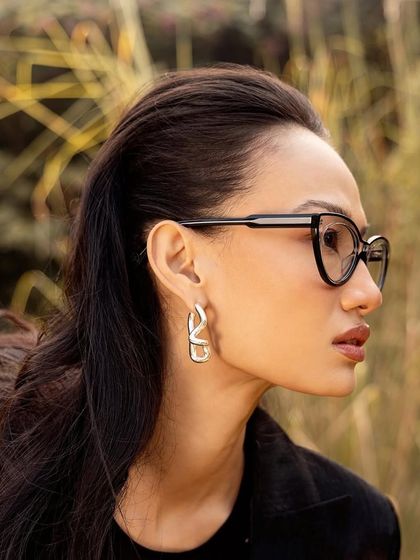 A profile shot focusing on a pair of modern, black cat-eye glasses from John Jacobs.