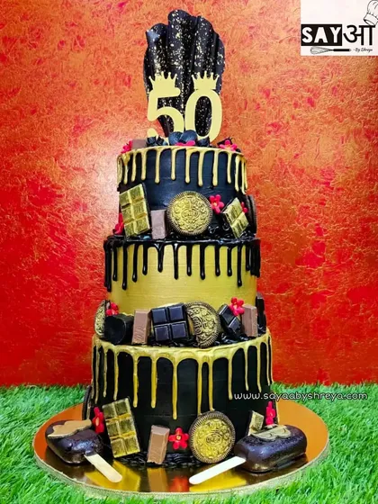 This massive three-tiered cake was for a golden 50th birthday. The black and gold theme exudes luxury, with chocolate drips, gold-dusted chocolates, and even mini cakesicles as part of the decoration.