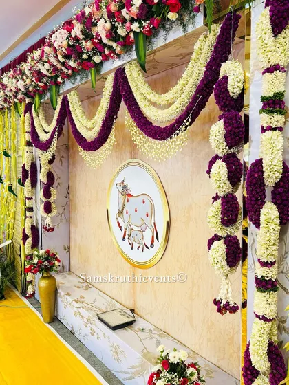 A close-up of our Pichwai-inspired backdrop, featuring the sacred cow motif and beautiful floral garlands. The combination of purple and white flowers creates a rich and royal look.