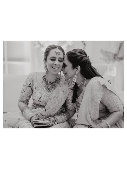 A quiet moment between sisters on the wedding day. A black and white photo capturing a whispered secret or a word of encouragement.