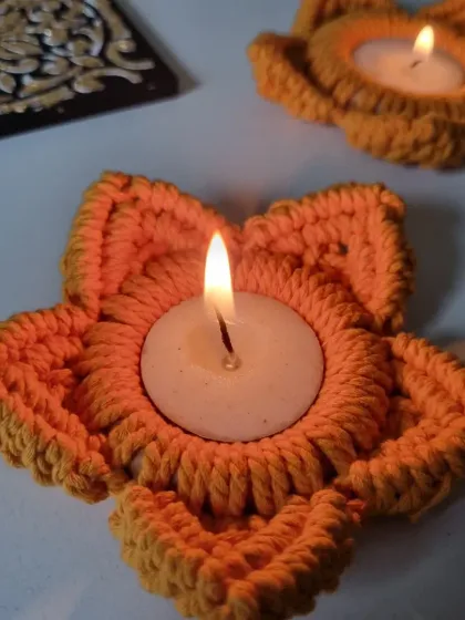 A close-up of the lit flower tealight holder, showing the beautiful texture of the macrame petals.