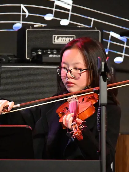 A young violinist completely focused during her performance. We nurture this level of dedication and precision in all our instrumental students.