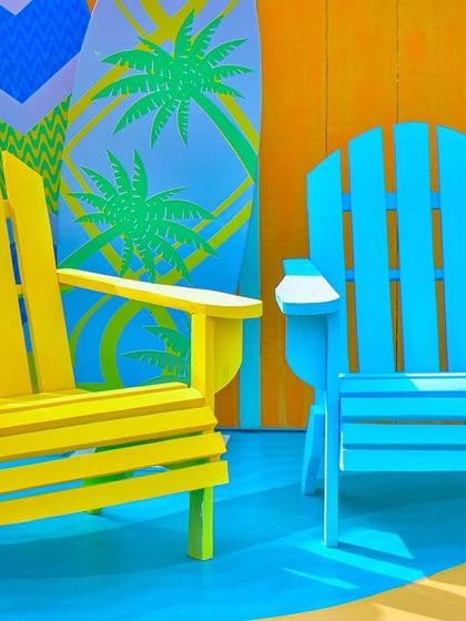 Colourful Adirondack chairs in bright yellow and blue create a cheerful and comfortable seating spot within the beach party's photo zone.