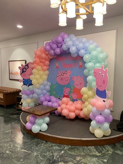 A side view of the Peppa Pig pastel rainbow balloon arch on a stage.