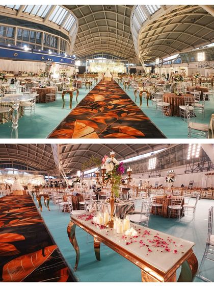 A panoramic view of a massive indoor reception hall we decorated. The long, patterned aisle runner and elegant table settings show the scale and grandeur of the event.