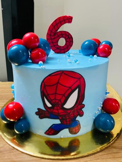 A cool blue Spider-Man cake for a 6th birthday, decorated with red and blue spheres.