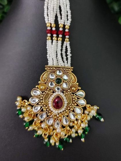 This beaded maang tikka features a pendant with both red and green stones.