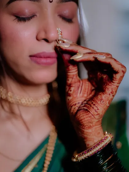 A detailed shot focusing on the bride's nath, henna, and nail art. Every little detail is considered to complete the look.