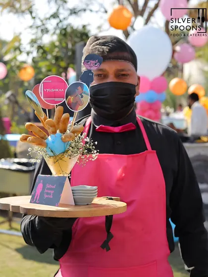 For a truly immersive experience, my staff and I embrace your event's theme. Here, one of my uniformed team members presents "Buttered Sausage Guards" at a Squid Game themed birthday, showcasing my commitment to creative, detailed event execution.