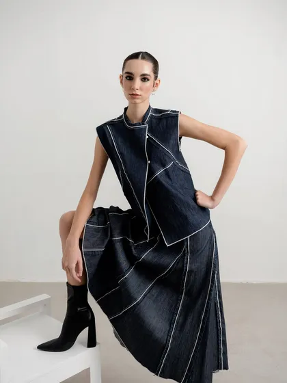 A minimalist studio shot for a contemporary womenswear brand. The styling is clean and sharp, focusing on the unique construction and contrast stitching of the denim two-piece. This demonstrates my ability to create compelling lookbook images that are both artistic and commercial.