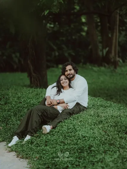 The couple embracing on a grassy hill, a sweet and romantic portrait in a natural setting.