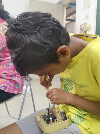 A young boy carefully disassembles a small appliance with a screwdriver. Our workshops provide a safe space for kids to explore their curiosity and learn how everyday household items work from the inside out.