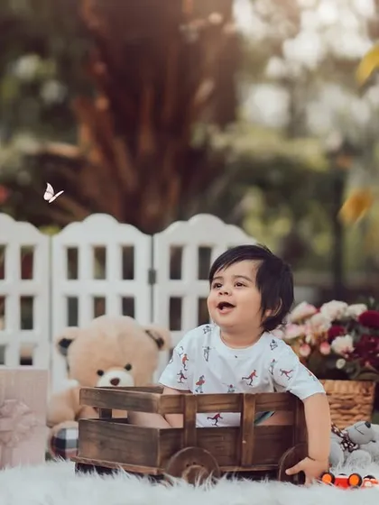 A classic first birthday portrait surrounded by his favorite things. This outdoor setup with "ONE" blocks and teddy bears creates a perfect scene to celebrate a year of wonderful adventures.