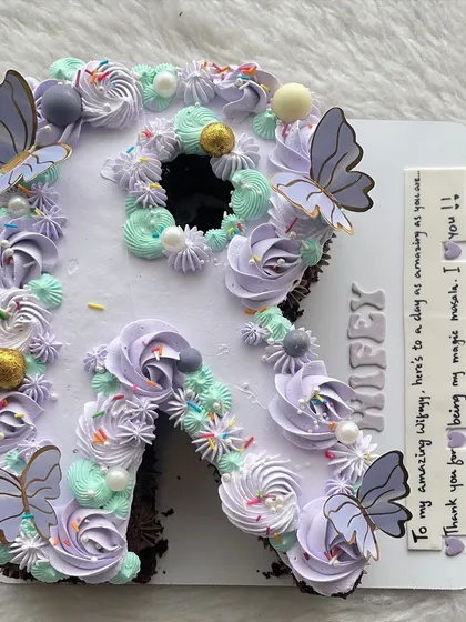A letter "R" cake in a beautiful lilac and mint green color scheme, adorned with butterflies for a magical touch.