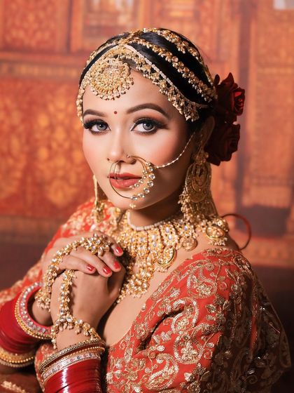 A classic bridal portrait. The model is wearing a full golden Polki set, including a choker, hathphool, and nath, against a traditional backdrop.