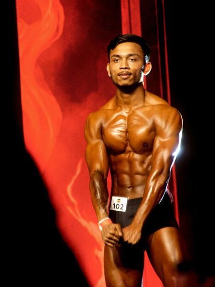Another confident stage shot. The lighting highlights his v-taper and defined abs, showcasing the hard work of his competition prep.