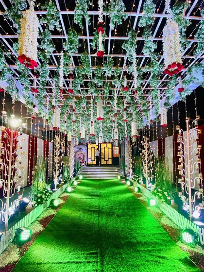 We created this enchanting passage for a Kali Puja event. The design features a ceiling of lush greenery with hanging red roses and traditional bells, creating a beautiful and devotional pathway for attendees.