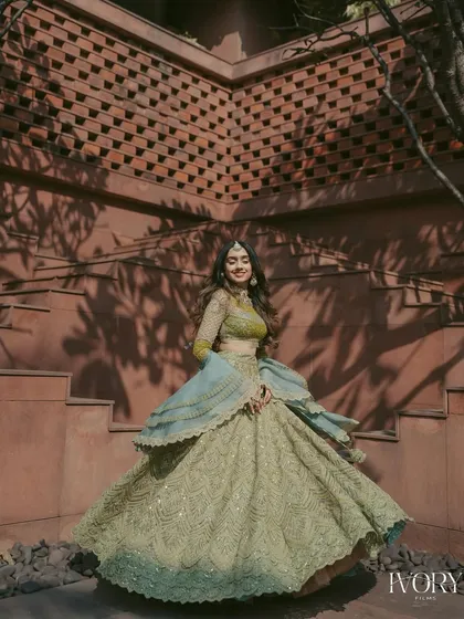 A full-length portrait of the bride twirling in her stunning Mehendi outfit, showcasing the intricate details and beautiful colors against a modern architectural background.