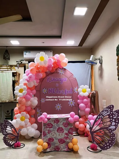 A whimsical butterfly and daisy theme for a first birthday. The custom pink arched backdrop is framed with a balloon garland featuring balloon daisies and accented with large butterfly cutouts.
