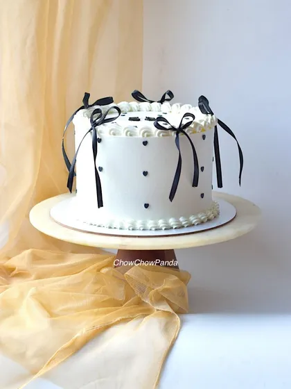 For a touch of classic elegance, I created this vintage-style cake. It has a clean white buttercream finish, decorated with simple black hearts and delicate black ribbons, offering a timeless and chic look for any celebration.