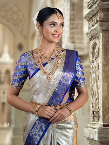 A three-quarter portrait of a model in a traditional South Indian saree. The background of carved pillars adds an architectural element and a sense of place to this elegant bridal fashion shot.