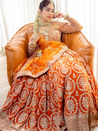 A regal pose in our burnt orange bridal lehenga. The detailed embroidery on the skirt and the rich color make this a standout choice for any bride.
