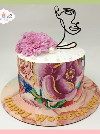 A beautiful and artistic cake for Women's Day, featuring a hand-painted floral design and a minimalist line-art face topper.