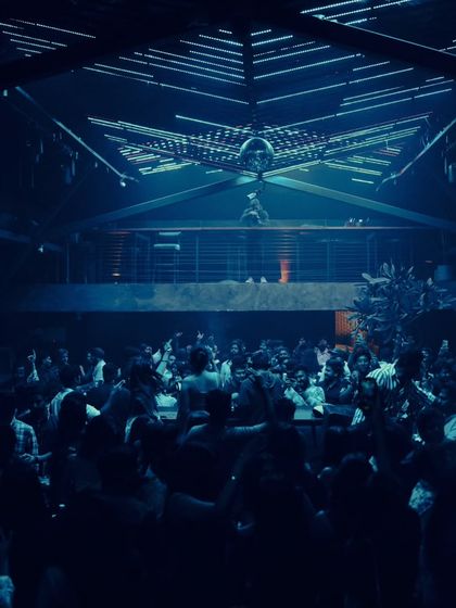 A wide shot of the two-story warehouse setup at Xora, Hyderabad. The blue light and disco ball create a classic club atmosphere.