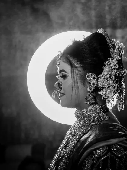 A dramatic black and white bridal profile, using a ring light to create a striking halo effect and highlight her ornate jewelry.