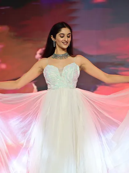 The model twirls on stage, showing the beautiful movement of the gown. The makeup remains fresh and radiant, catching the stage lights beautifully.
