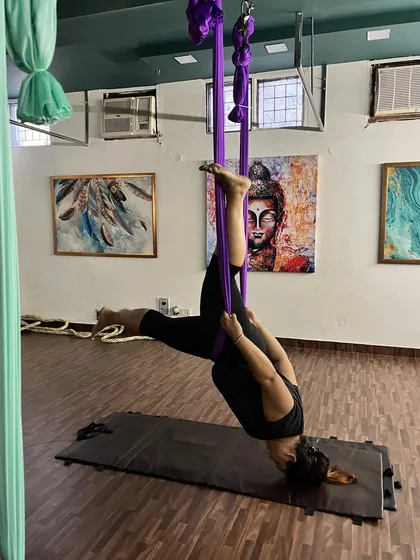 This inverted pose, supported by the purple silk, is not just a physical challenge but also a mental one. It teaches trust and surrender, key elements of the yoga journey.