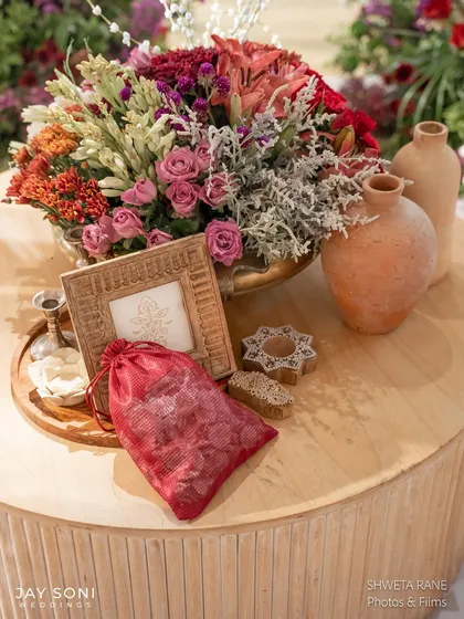 A collection of decor items on a side table, including a floral arrangement, terracotta vases, and a custom-printed favor bag.