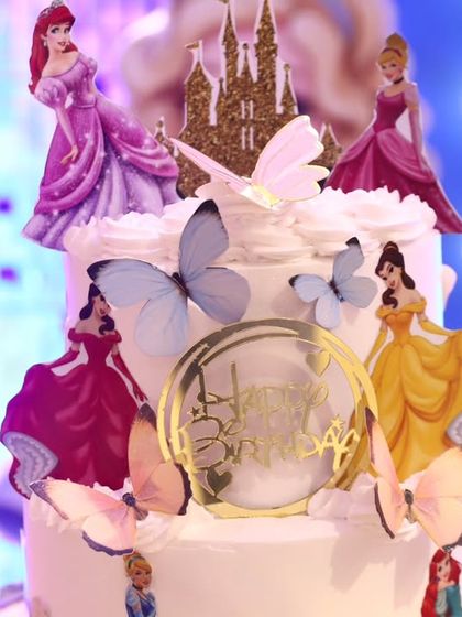 A detailed shot of the princess birthday cake, adorned with figures of various Disney princesses and butterflies.