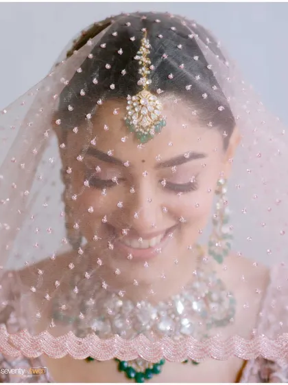 A soft, dreamy close-up of the bride smiling, seen through her delicate veil. A beautiful and ethereal bridal portrait.