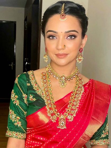 A classic red and green bridal combination. The makeup features a clean, sharp wing and a beautiful red lip, creating a timeless look for her wedding day.