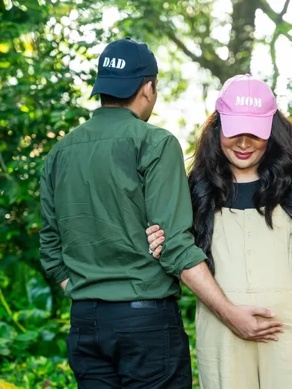 A playful and creative way to announce they're expecting. The "Mom" and "Dad" caps add a touch of fun to this outdoor maternity portrait.
