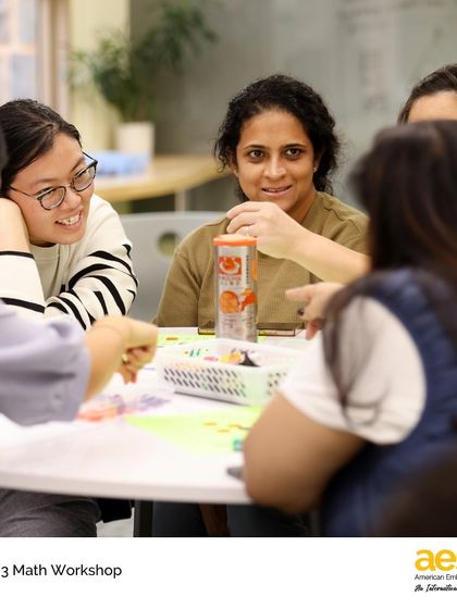 Parents collaborate on a math game during a workshop. We provide resources and ideas to help families connect learning at home with what's happening in the classroom.