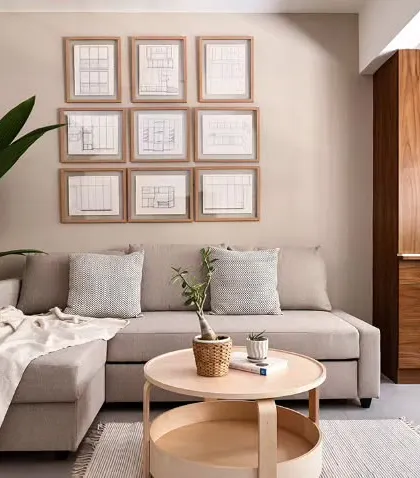 This living space from our "Rooted Japandi Home" renovation project showcases a fusion of Japanese and Scandinavian design principles. A custom puja unit with a geometric CNC-cut pattern stands beside a comfortable sofa, while the gallery wall features the client's late father's own carpentry sketches, rooting the modern design in family history.