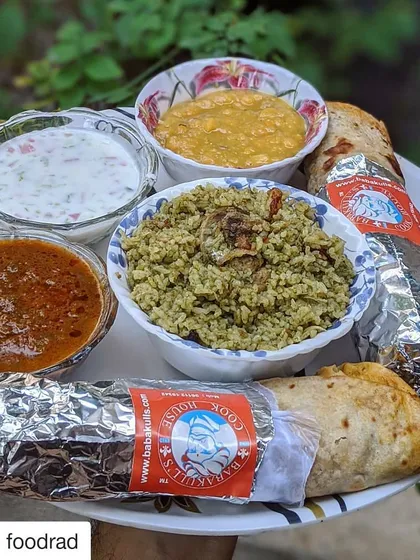 This is what a meal from my cook house looks like when served at home. You can see the rich biriyani rice, bowls of spicy salan and fresh raita, and our foil-wrapped rolls, ready to be enjoyed. It’s a taste of tradition, delivered right to you.