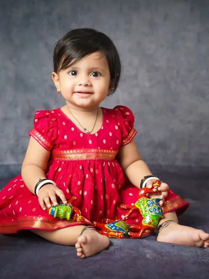 Celebrating Sanskrit Day with a traditional themed shoot. This little girl looks adorable in her red dress with Indian toys.