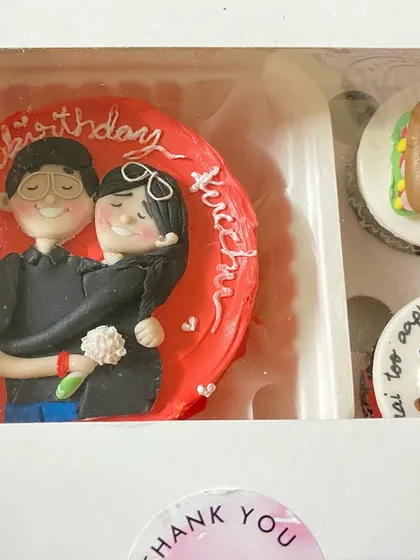 A close-up of one of our favourite bento and cupcake combos. This set features a hand-painted Nutella hazelnut bento cake with a couple's portrait, paired with cupcakes showing their inside jokes like "our forever 3 am meal".