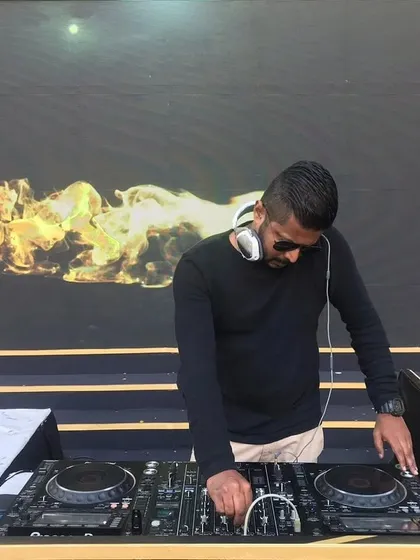 A full shot of me at the decks during an outdoor event, with a cool fire graphic on the screen behind me.