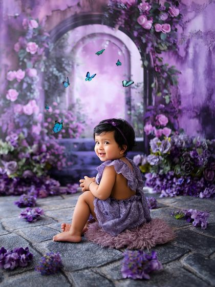 A lovely portrait of this baby girl looking back with a sweet smile in her purple wonderland.