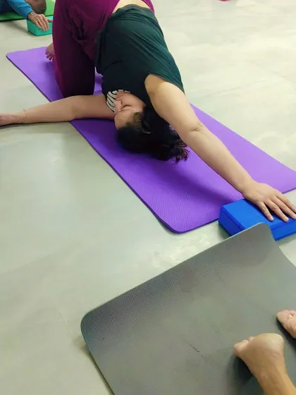 A member practices a gentle twist using yoga blocks for support. Props make yoga accessible to everyone, regardless of their flexibility level.
