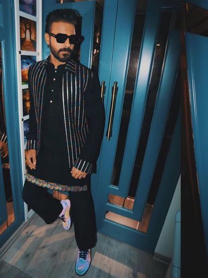 A masterpiece of modern festive wear. This black kurta is paired with a striking silver-striped bandi jacket, worn here by artist Naitik Nagda.