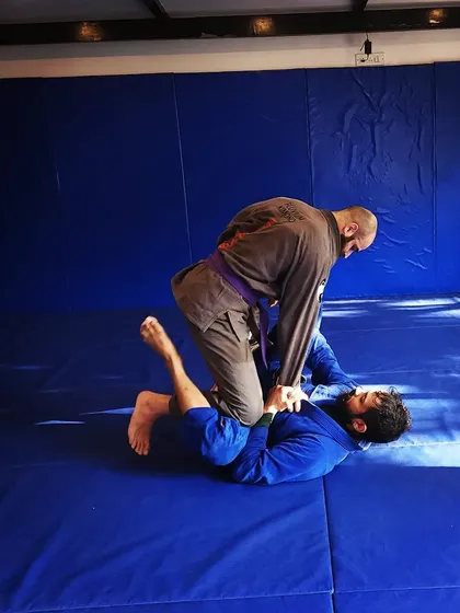 A coach demonstrates a guard pass while a student defends. This is how we learn through practice.