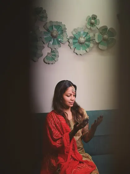 A quiet moment of contemplation for the bride as she admires her freshly applied henna. The framing creates a sense of intimacy, focusing on this important pre-wedding ritual.