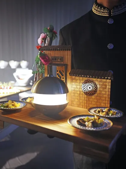 A server presents a tray of our finest appetizers, featuring miniature houses, at a high-profile 40th birthday party.