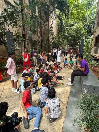 An instructor plays a stringed instrument for a group of captivated children during an outdoor weekend session, sharing the stories and sounds of Brazil.