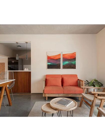 This informal seating area showcases our use of natural materials and pops of color. The wooden furniture with cane accents and the orange sofa create a warm and inviting atmosphere, perfect for casual family gatherings.
